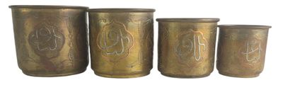 four antique brass canisters are lined up against a white background
