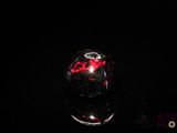 une image représentant une boule en verre rouge et noire posée sur une surface noire