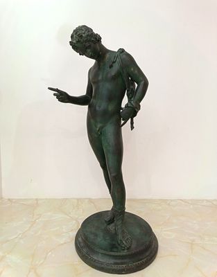 bronze statue of a man holding a knife and pointing at something