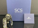 une figurine en verre représentant un homme tenant une cigarette devant une boîte bleue