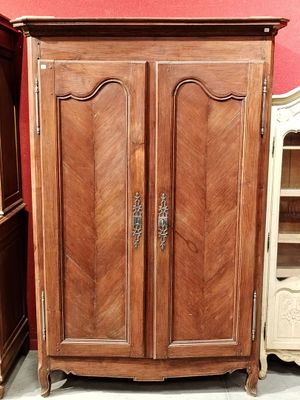 une armoire en bois à deux portes avec une étagère, placée devant un mur rouge