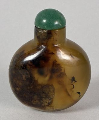 a small glass bottle with a green lid on a white surface