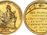 a gold coin with an image of a woman sitting on a throne
