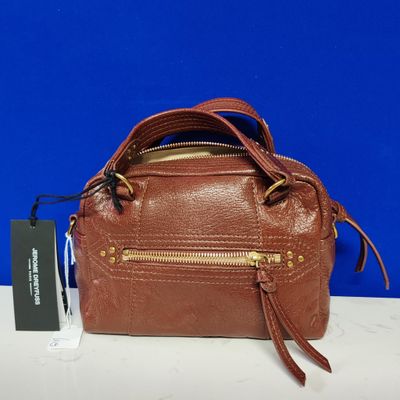 Le sac à main marron est posé sur une table blanche, sur fond bleu.