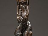 a bronze statue of a woman sitting on top of a table