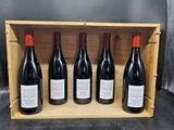 quatre bouteilles de vin rouge dans un coffret en bois posé sur une table