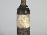 une vieille bouteille de vin posée sur une table blanche