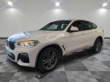 un SUV BMW blanc garé dans un garage au sol carrelé
