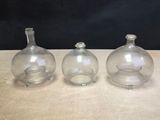 three clear glass vases sitting on top of a wooden table