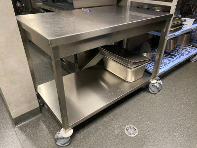 a stainless steel work table with a metal shelf on it