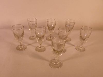several empty wine glasses are lined up on a white table