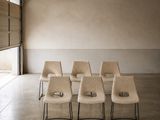 Plusieurs chaises sont alignées dans une grande pièce dotée d'une porte coulissante en verre.