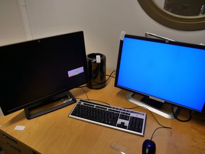 deux écrans et un clavier posés sur un bureau devant un miroir