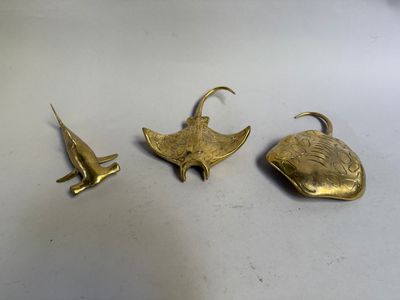 trois pièces en laiton sont posées sur une surface blanche