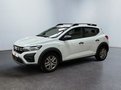 Une voiture blanche est garée dans une pièce au sol noir.