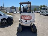 the back end of a small white tractor parked in a parking lot