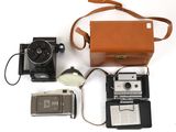un appareil photo, un étui pour appareil photo, un téléphone portable et un appareil photo posés sur une surface blanche