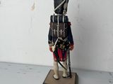 wooden toy soldier with a red and black uniform on a wooden base
