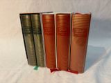 three books are lined up on a white surface with a green ribbon