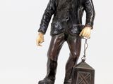 statue of a man with a backpack and a suitcase on a rock