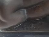bronze statue of a man with his arm resting on the ground