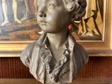 statue of a woman in a dress and a painting in the background