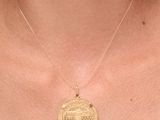 un gros plan d'une personne portant un collier orné d'une pièce de monnaie