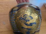 une personne tenant un vase bleu et doré posé sur une table en bois