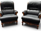 une paire de fauteuils inclinables en cuir noir, avec des accoudoirs et des pieds en bois sculpté