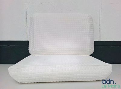 le dossier d'une chaise blanche sur lequel est posé un coussin