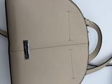 beige leather handbag on a white surface next to a cell phone