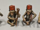 three figurines of monkeys with drums and hats on their heads