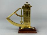 an antique brass sundial on a wooden base on a grey background