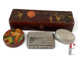 three tins and a box sitting on a white surface