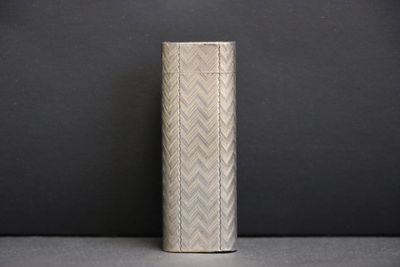 un vase en argent posé sur une table, sur fond noir