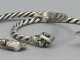 two silver bracelets on a table with a silver bead on the end