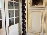 une grande colonne en bois dans un salon doté d'une porte vitrée