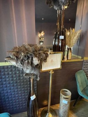 a vase with feathers on a stand in a room