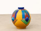 brightly colored vase sitting on concrete surface with white wall in background