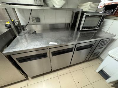 stainless steel counter top in a commercial kitchen with a microwave and dishwasher