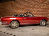 an image of a red convertible car parked in front of a brick wall
