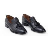a pair of black leather shoes with tassels on the sole