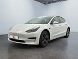 une Tesla Model 3 blanche garée dans une pièce blanche