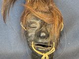 an image of a black mask with hair on a blue background