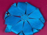 a blue flower brooch on a pink surface