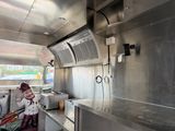 a woman that is standing in the kitchen of a food truck