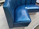 a blue leather bench with a metal base on the ground