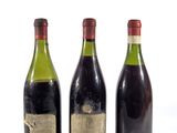 trois bouteilles de vin posées les unes à côté des autres sur une surface blanche