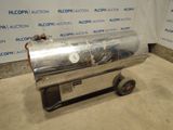 une photo d'un barbecue en acier inoxydable monté sur roulettes, devant un mur