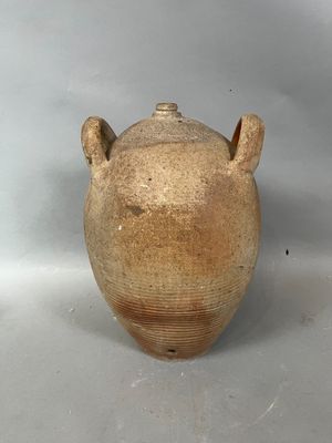 un vase marron muni de deux anses, sur un fond blanc
